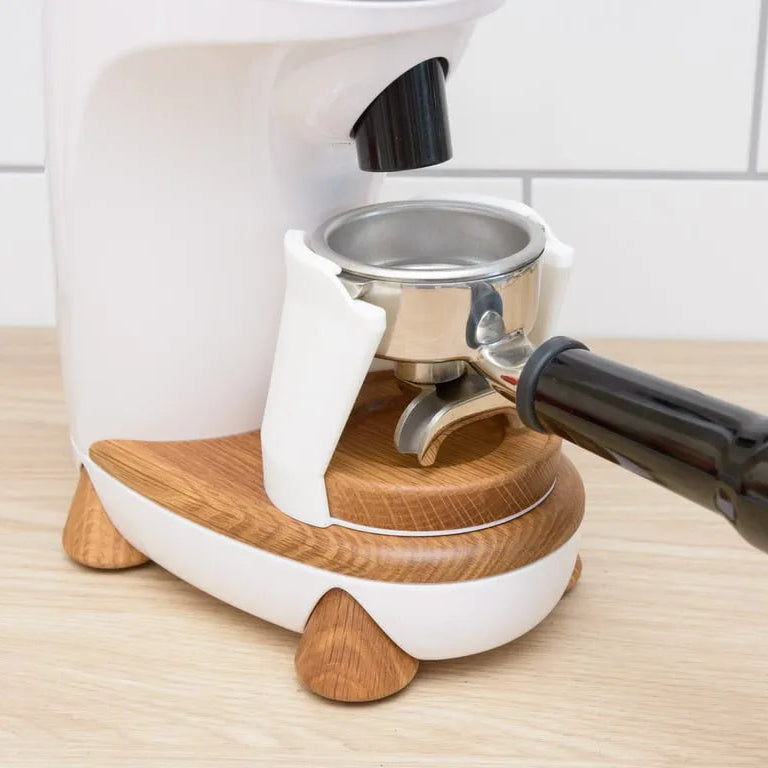 White espresso machine with wooden accents on a wooden surface.