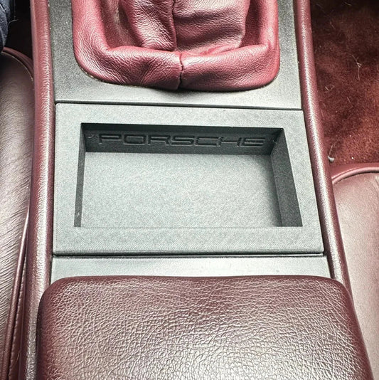 Car interior with a Porsche logo on a gray panel.